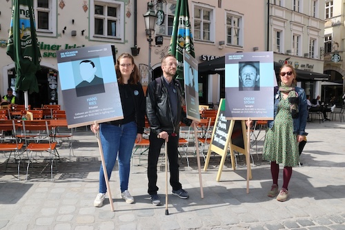 Drei Personen stehen mit den Tafeln der Opfer. In der Mitte steht Wolfgang Vogl