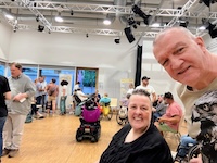 Im Hintergrund viele Teilnehmende zu sehen, im Vordergrund ein Selfie von Jackie und Udo Ernst