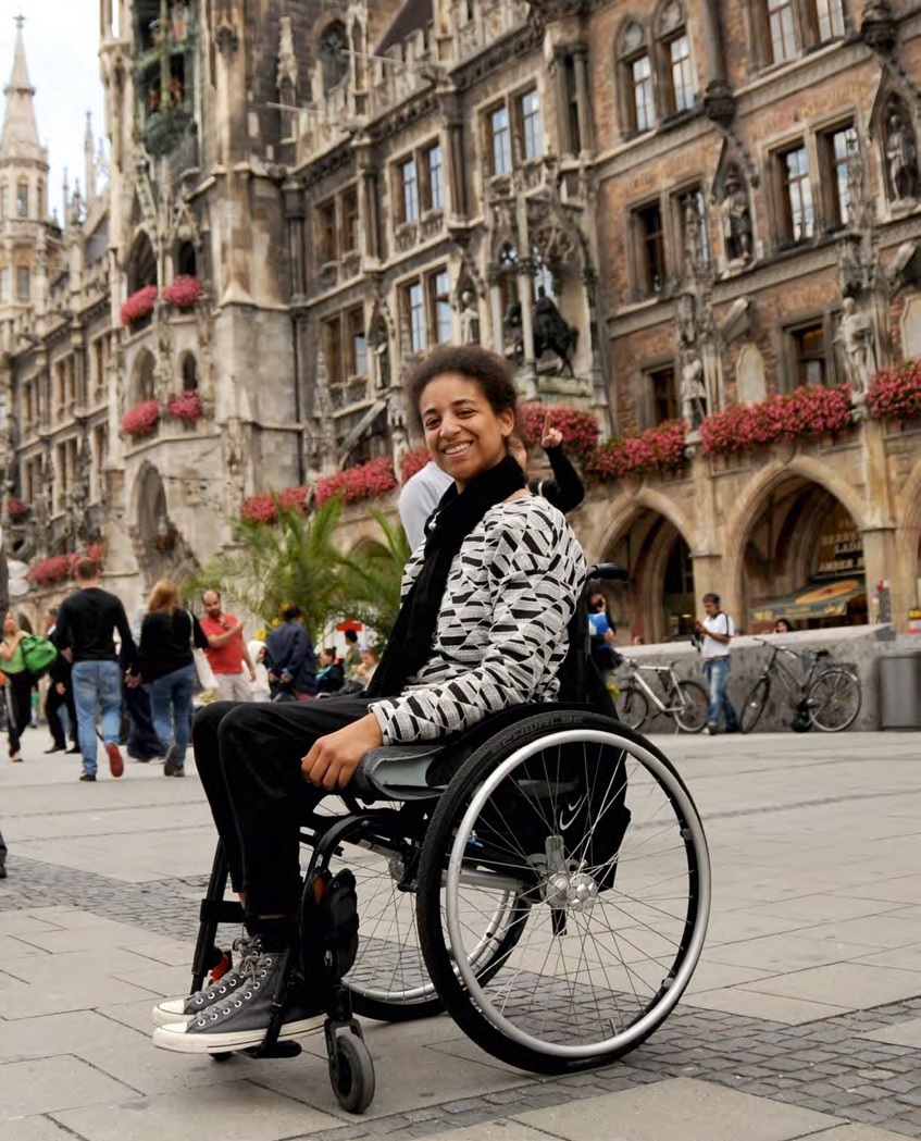 Junge fröhliche Frau im Rollstuhl auf dem Marienplatz